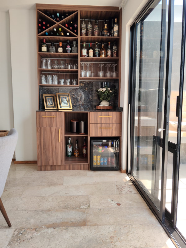 Mueble bar residencial en Puebla con cubierta y respaldo de porcelánico instalado por Alpetri.
